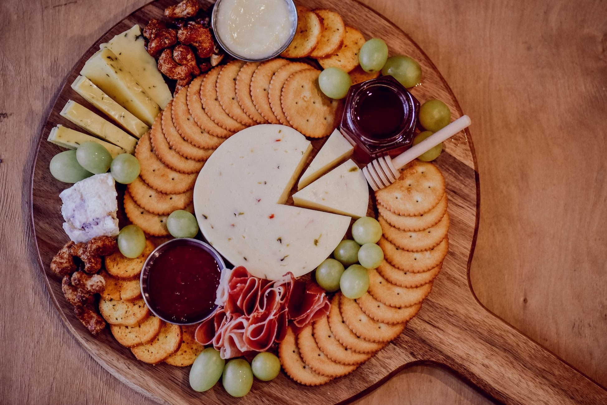 A beautifully styled empowerment charcuterie board with a variety of cheeses, fruits, nuts, biscuits and ham surrounded by fresh yogurt.