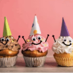 Colorful cupcakes with party hats dancing on a festive table, perfect for DIY birthday celebration ideas at home.
