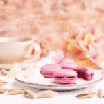A beautifully arranged plate of rosewater and raspberry macarons with fresh raspberries, tea and edible flowers, perfect for a special occasion.