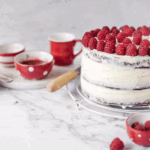Hands holding the cake white frosted pink velvet cake topped with a fresh strawberry, perfect for special occasions.