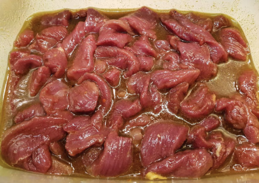 Beef slices marinating in a bulgogi sauce mixture of cola, soy sauce, brown sugar, garlic, and grated onion.