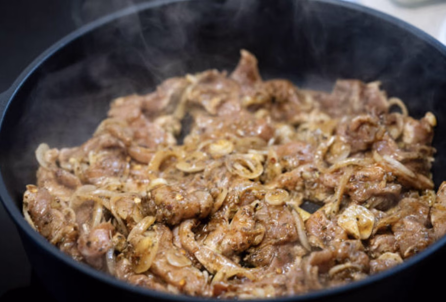 Simmering bulgogi marinade in a skillet reducing into a thick, glossy sauce.