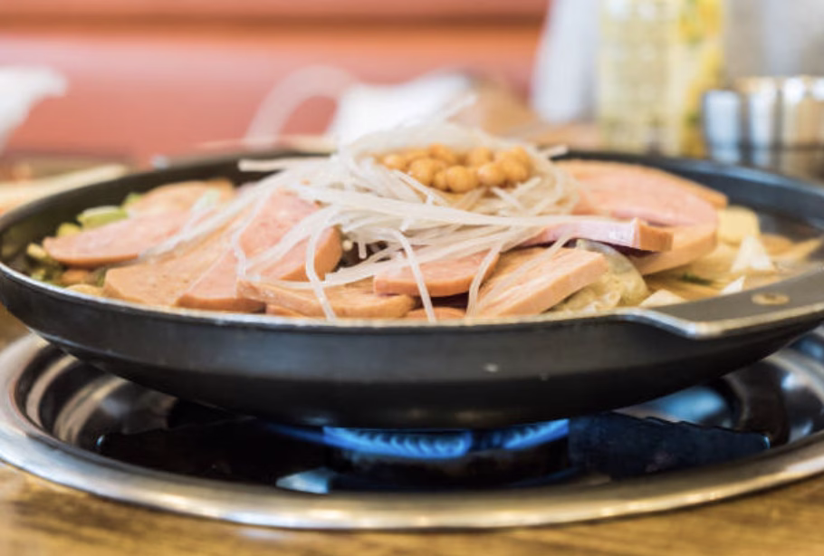 Sizzle the base of your Army Stew Korean by sautéing kimchi, onions, and Spam.