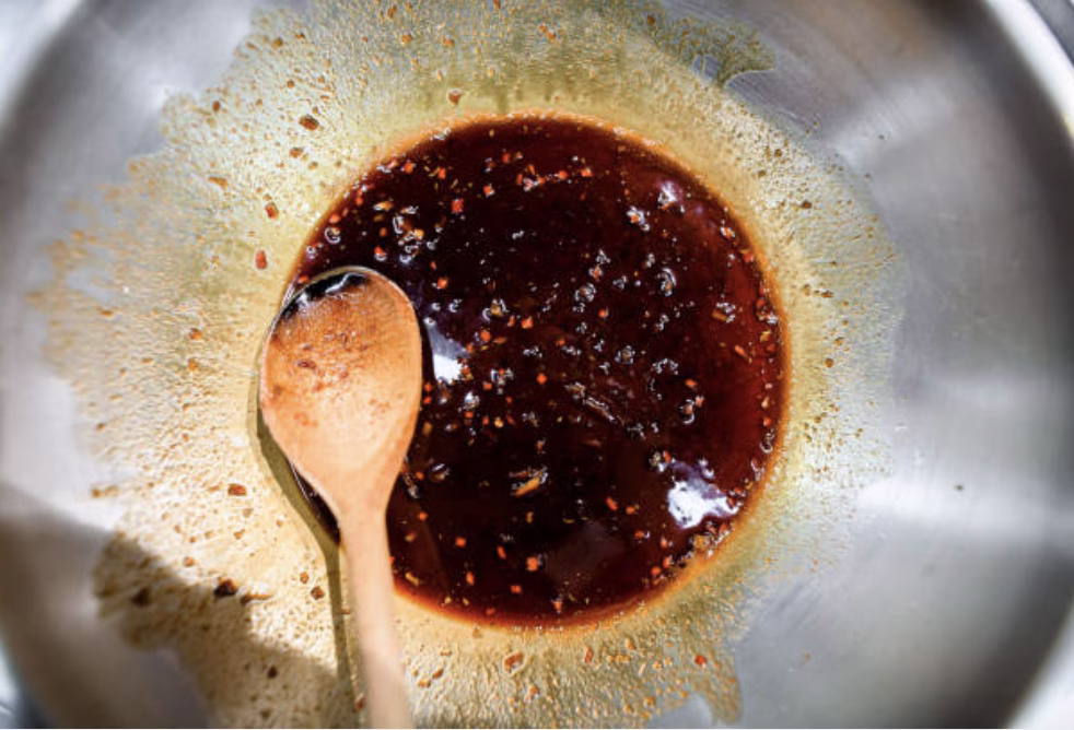 Simmering gochujang-based sauce in a saucepan for Korean fried chicken.