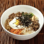Assembled bibimbap bowl with rice, vegetables, beef, and fried egg.