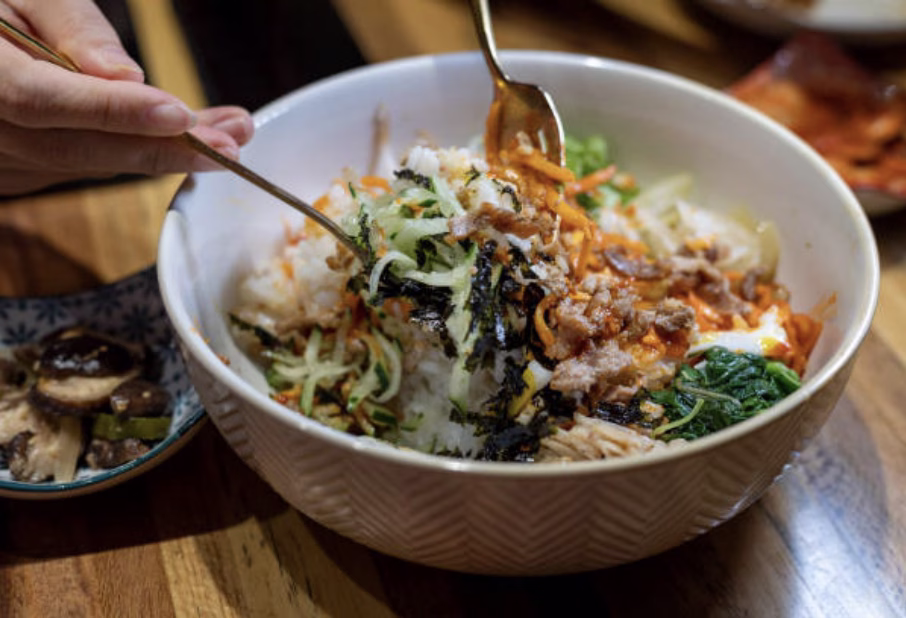 Mixed bibimbap with rice, vegetables, beef, and egg combined in a bowl.