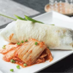 Tortilla wrap filled with scrambled eggs, spam, and kimchi, exemplifying a Korean-American fusion breakfast.