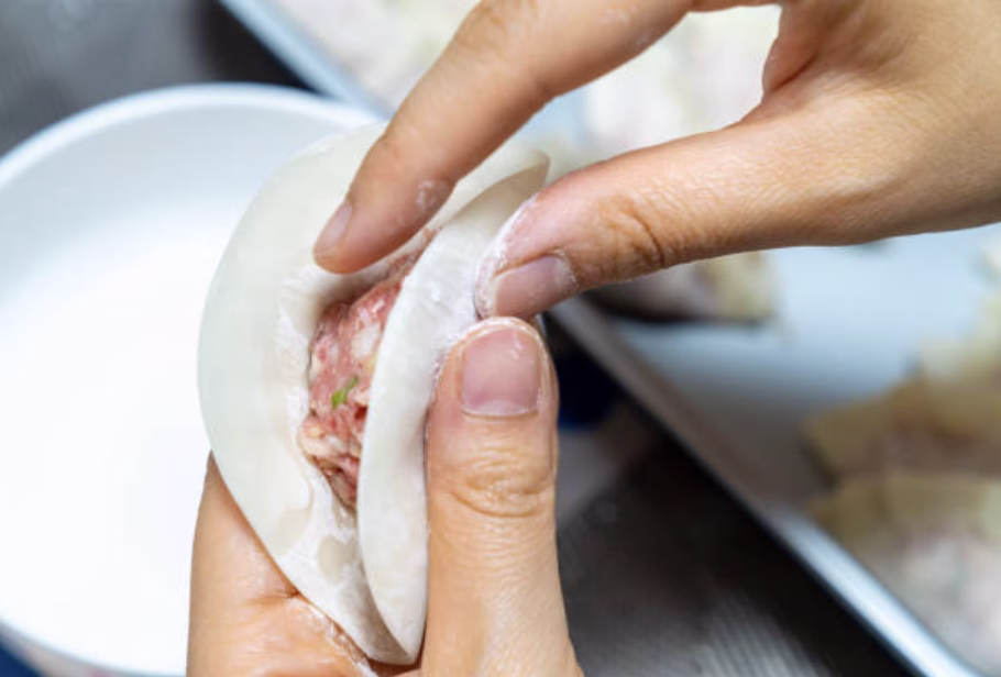 Mandu being sealed with a fork on a cutting board