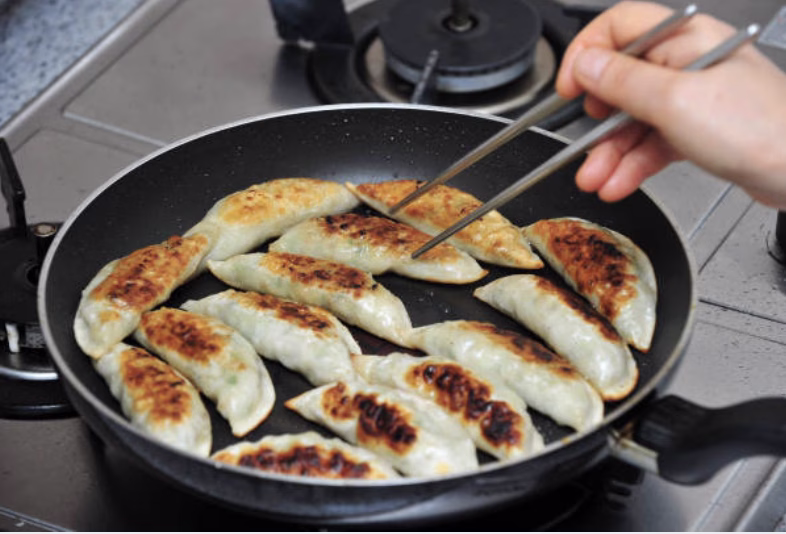 Crispy yaki mandu frying in a pan until golden brown