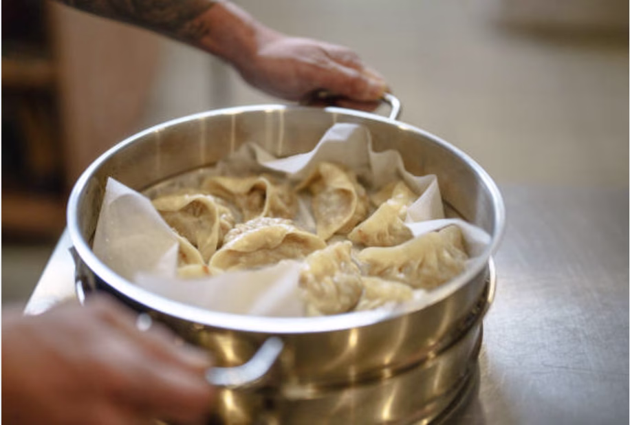Steamed mandu resting on parchment inside a bamboo steamer