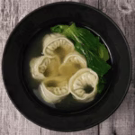 Korean mandu guk with dumplings, eggs, and spinach in clear broth