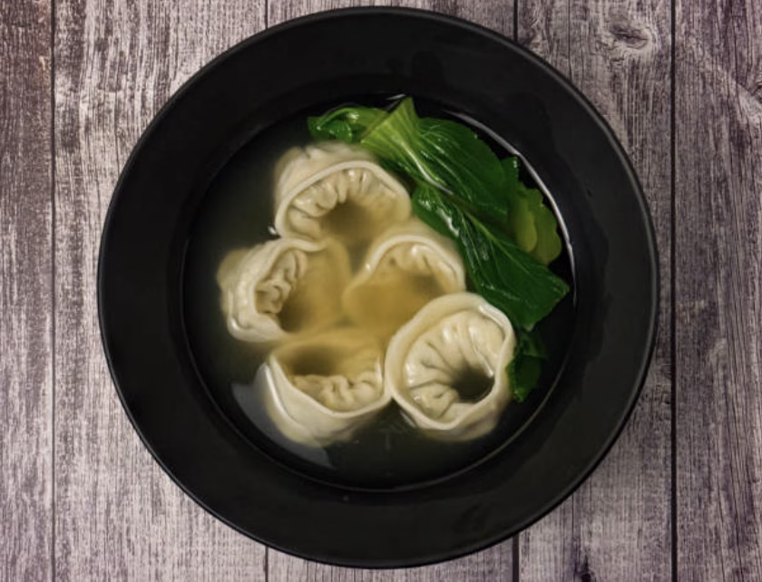 Korean mandu guk with dumplings, eggs, and spinach in clear broth